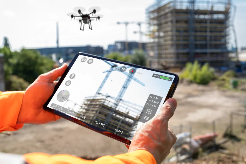 建設現場でタブレットを手に持ち施工状況を確認する作業員