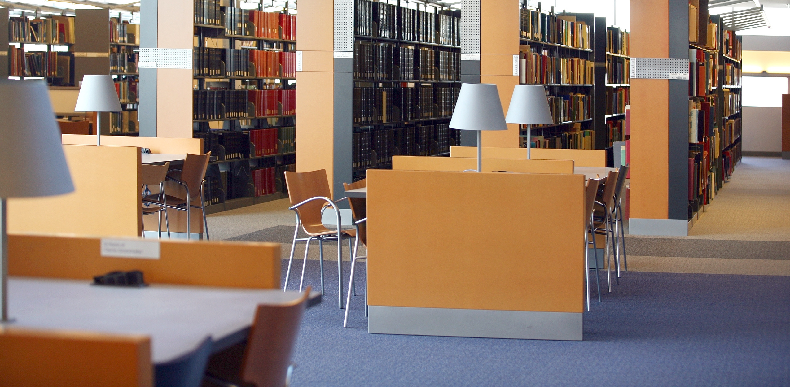 図書館内観、閲覧テーブルと重厚な書架が並ぶスペース