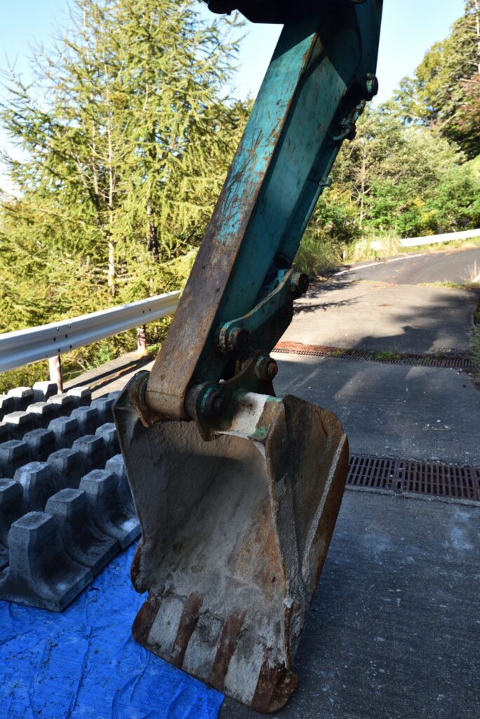 山間部の道路脇で作業する油圧ショベル