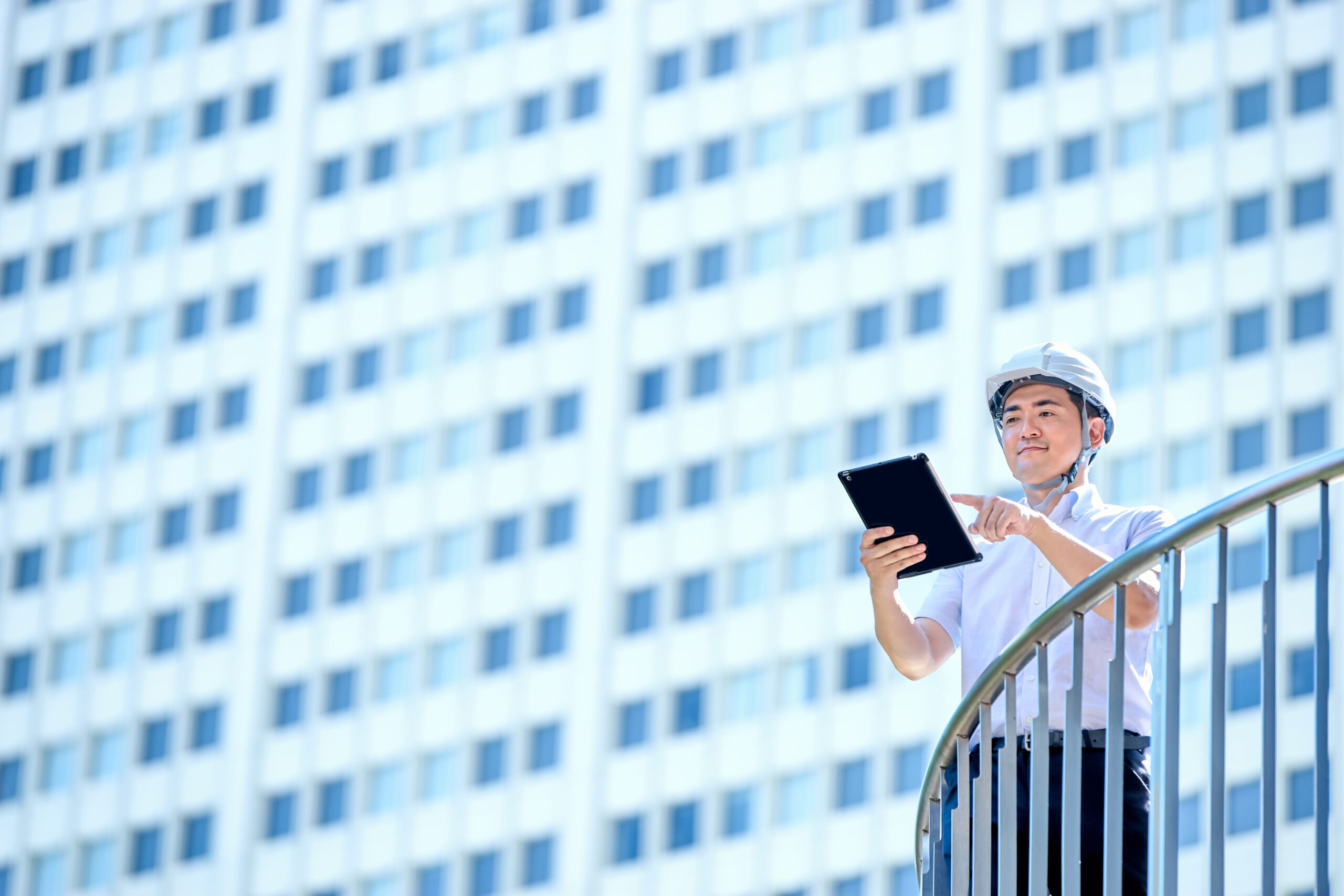 建物を背にタブレットで3次元モデルを確認する現場技術者